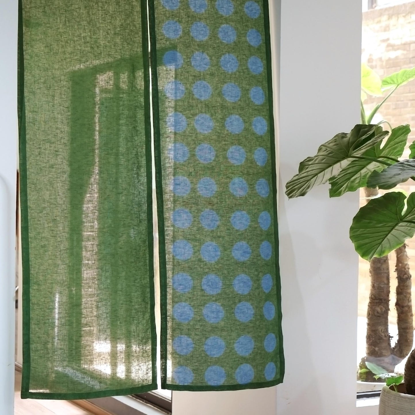 alternate angle of Polka Dot Linen Noren — Green / Dots hanging as a two-panel doorway curtain